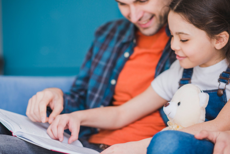 Papá con cuaderno enseñando a su hija de más de 10 años de edad, con peluche en mano, todo acerca de una cuenta bancaria