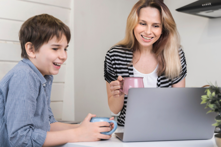 Cuenta para menores de edad en el Venezolano de Crédito Niño con taza azul en la mano y mamá con taza rosada, ambos sonrientes, viendo la pantalla de laptop