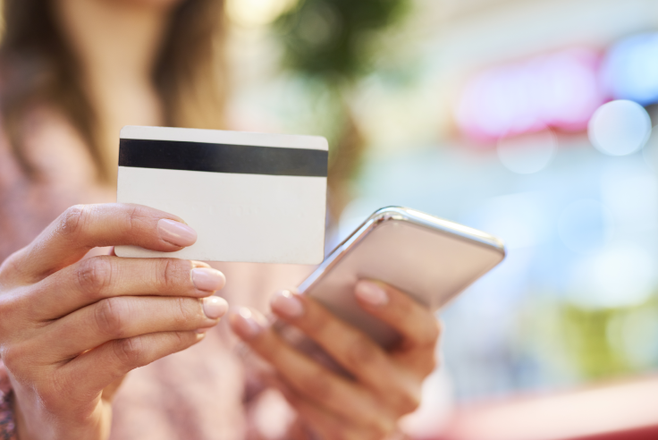 Cuenta Digital Mujer realizando un pago digital con un teléfono móvil y una tarjeta de débito en sus manos