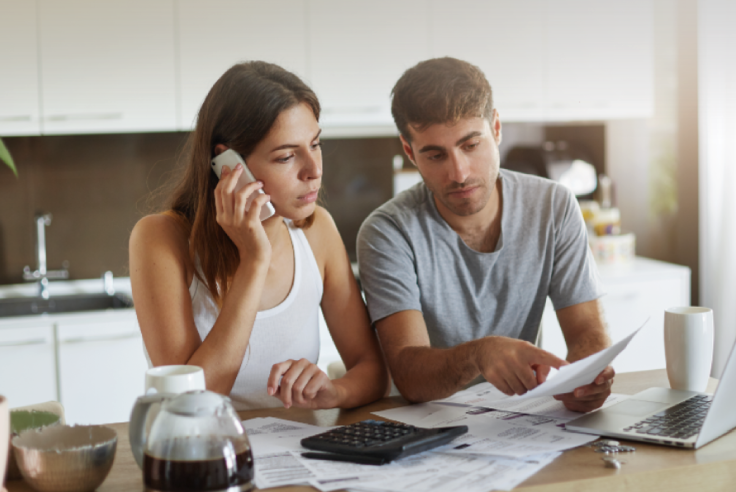 Mujer joven saca cuentas imaginarias mirando hacia arriba, preguntándose comisión bancaria por usar su tarjeta y App