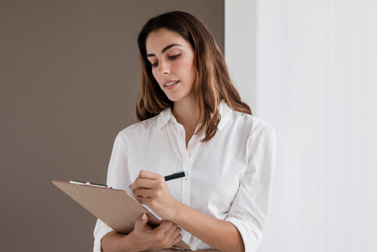 Mujer joven de pelo largo anotando en libreta