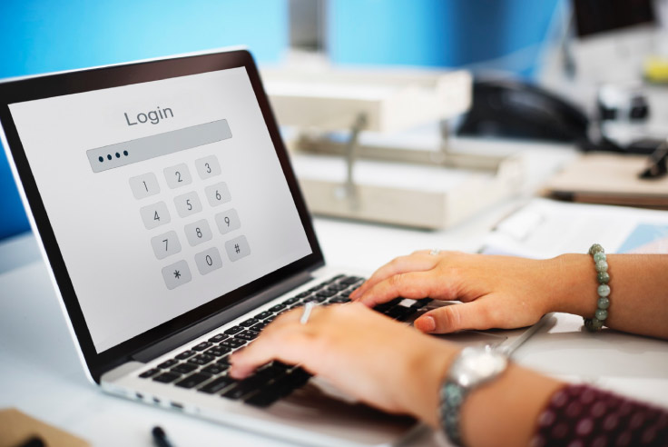 Persona escribiendo en una laptop, la pantalla muestra una interfaz de login con un teclado numérico