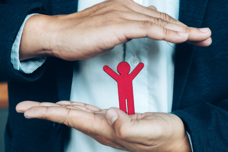 Conceptos de ciberseguridad Profesional o ejecutivo en traje demostrando máxima protección al cubrir y resguardar un dibujo de figura humana roja entre ambas manos