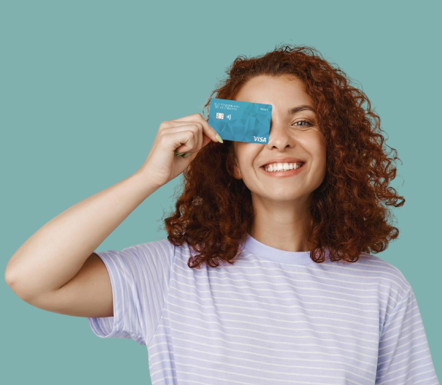 Chica joven de pelo crespo sostiene su tarjeta Visa CheckCard Prepaid de Cayman Branch, tapando su ojo derecho