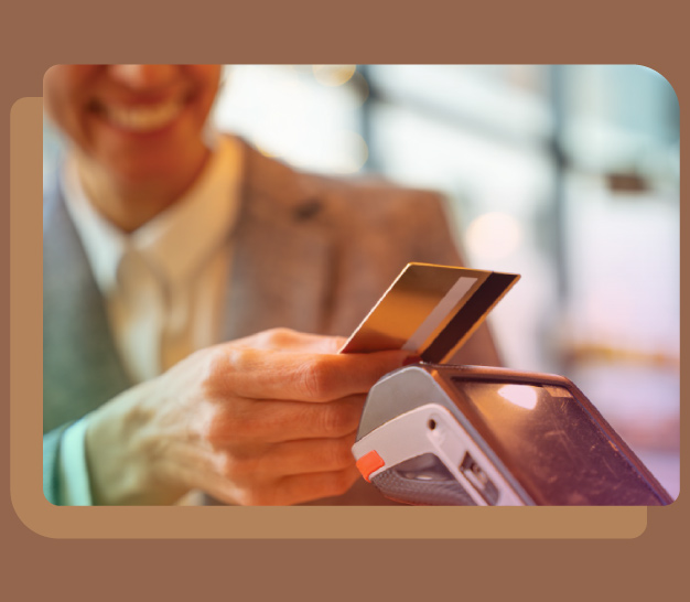 Detalle de la sonrisa de un hombre vestido de traje al pagar con su tarjeta bancaria contactless en un punto de venta